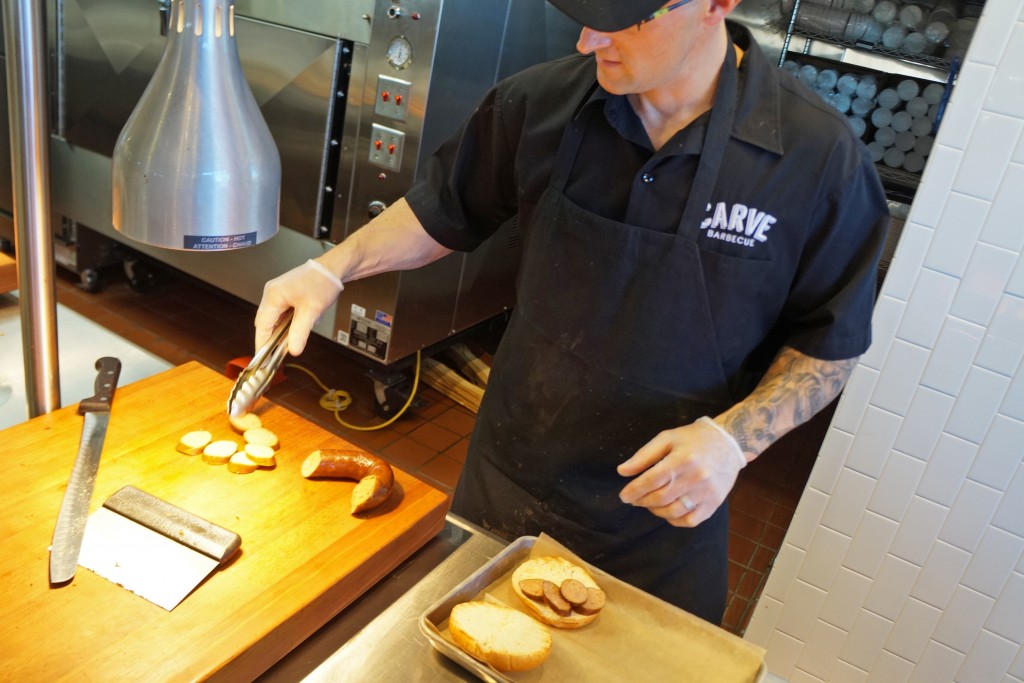 A Carve chef prepares a kielbasa sandwich with meat from locally based Polidori Sausage. Photos by Amy DiPierro.
